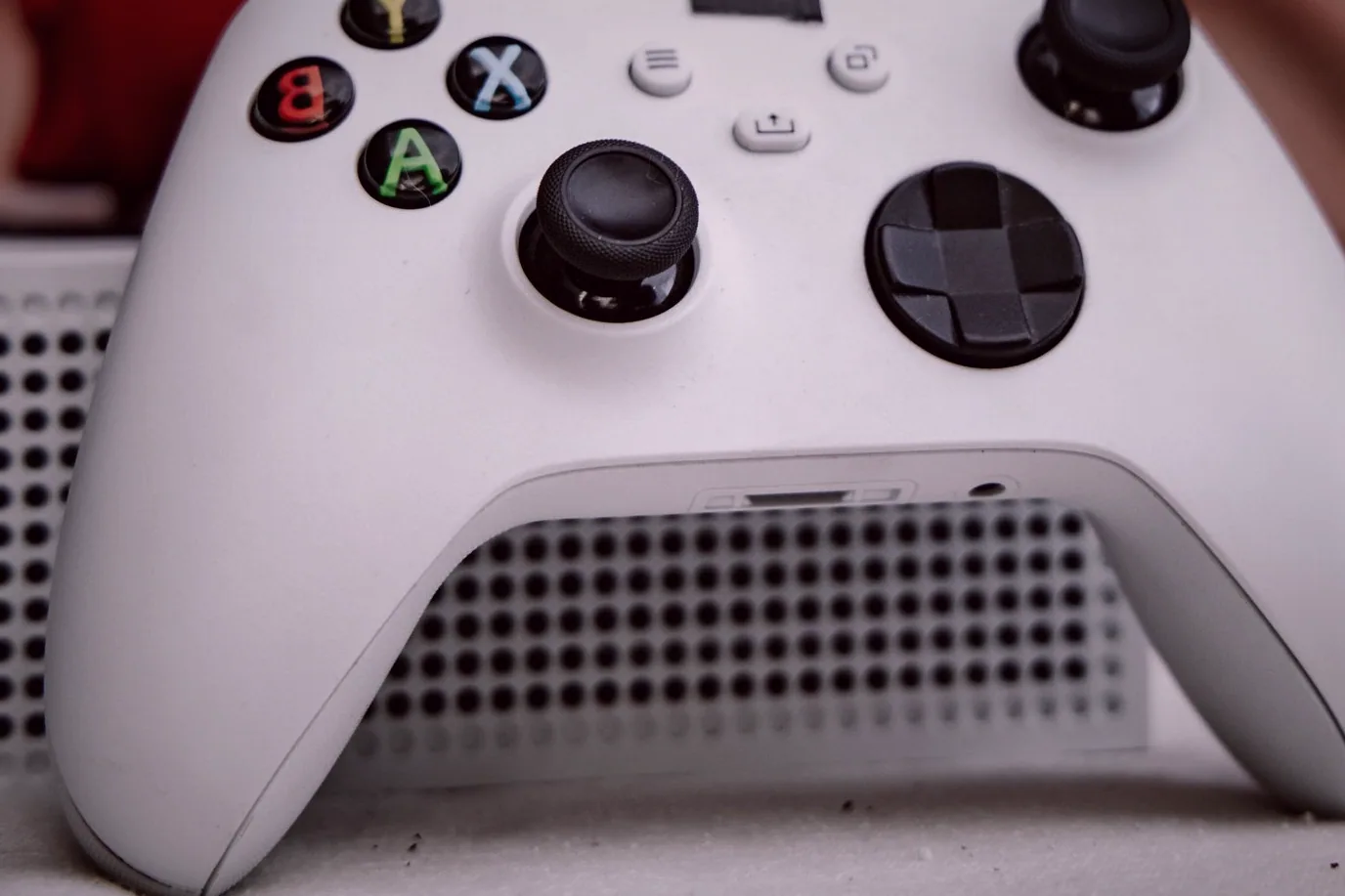 A controller resting on a couch arm beside a screen