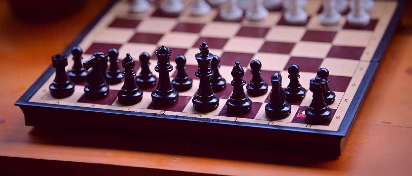 Players leaning over a board game with tiles and wooden markers